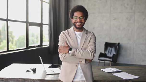 一位面带笑容的快乐的非洲裔美国商人自信地站在宽阔的办公室环境中 他的聪明弥补了他的现代职业风采 — 图库视频影像