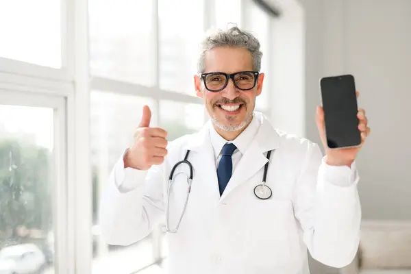 Lekarz Stetoskopem Szyi Daje Kciuki Góry Trzymając Telefon Pustym Ekranem — Zdjęcie stockowe