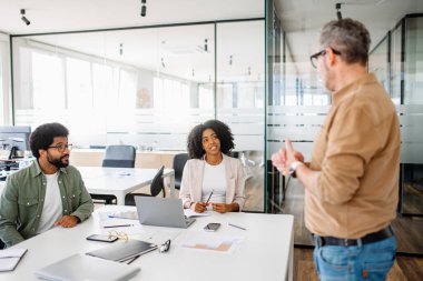 Takım, ofiste gelişigüzel bir beyin fırtınası seansının yapıldığı sunumu dikkatle dinliyor. Sunucu, takıma stratejik sezgilerde rehberlik ediyor, liderlik yaklaşımını somutlaştırıyor.