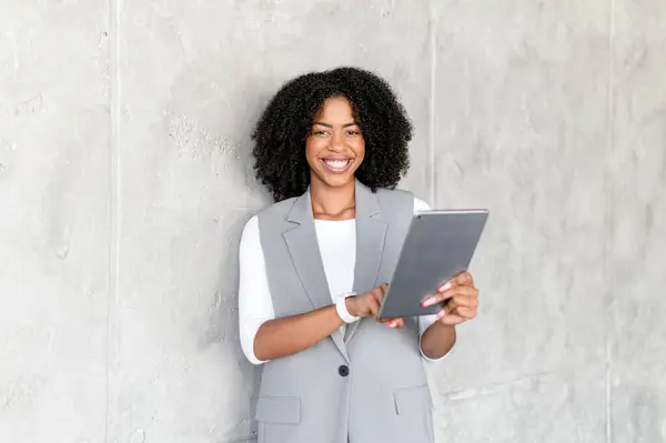 Eine Überschwängliche Afroamerikanische Geschäftsfrau Professioneller Kleidung Hält Ein Digitales Tablet Stockbild