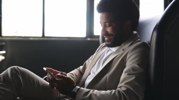 Молодой Современный Бизнесмен Элегантном Бежевом Костюме Удобно Сидит Пользуясь Смартфоном — стоковое видео