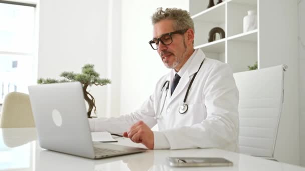 Dojrzały Lekarz Białym Płaszczu Wita Się Laptopie Podczas Wizyty Online — Wideo stockowe