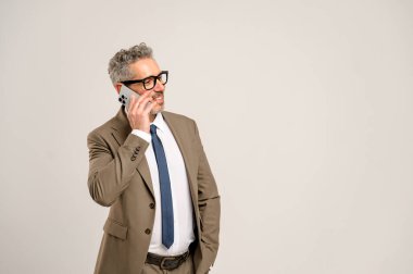 60 'ların yaşlı, gri saçlı iş adamı. Dostça gülümseyen, akıllı telefondan konuşan, ulaşılabilirlik gösteren ve teknolojiyle modern yönetim ilişkileri olan biri..