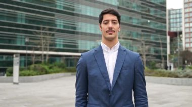 İspanyol iş adamı parlak bir gülümseme ile resmedilmiş, güçlü bir duruşta kollarını kavuşturmuş, bu da ilerideki iş sorunlarına karşı güvenin ve hazırlığın bulanık kentsel bir ortama karşı kurulduğunu gösteriyor..