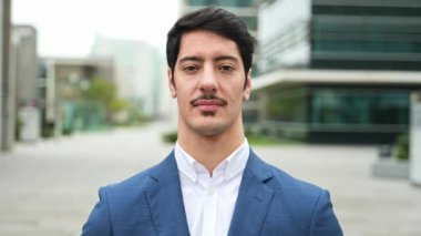Sıcak bir gülümseme ve modern binaların geçmişiyle bu yakışıklı İspanyol işadamı güven ve profesyonelliği sembolize eden mavi takım elbisesiyle kendinden emin bir şekilde duruyor..
