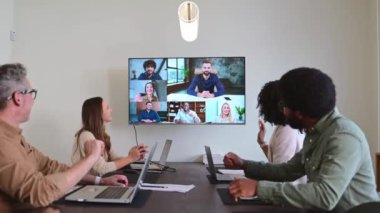 Üretken bir video konferansına katılan profesyonellerden oluşan bir ekip, konferans odasındaki büyük ekranda kişisel ve uzaktan katılımcıları birleştiriyor. Hedeflere ulaşmada etkili iletişim araçları