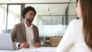 Afro-Amerikalı iş adamı, geniş bir ofis ortamında, işbirliği ve takım çalışmasını gösteren bir toplantı sırasında bir bayan meslektaşıyla konuşuyor. Mesleki değişim ve ortaklık kavramı