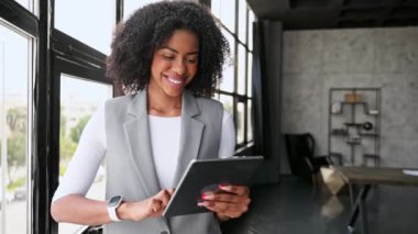 Kadının ofiste tabletini kullanmaktan zevk aldığı sıradan bir profesyonellik anı yakalıyor. Hoş gülümsemesi teknolojiyle verimliliği ve kolaylığı gösteriyor..