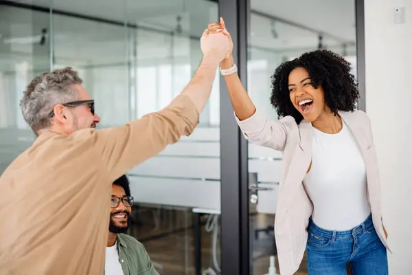 stock image A high-five moment captures the joyful success within a team, as a woman beams with pride and a colleague applauds, showcasing a supportive and uplifting office culture. Value of team achievements