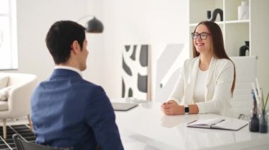 Modern bir ofiste bir erkek ve bir kadın beşlik çakıyor, kutlama ve başarı anlarını yakalıyorlar. Bu jest, bir iş görüşmesi ya da röportajın olumlu sonucunu gösterir.