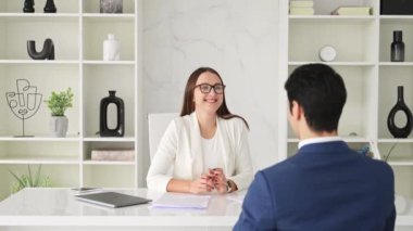 Mavi takım elbiseli bir adam ve beyaz ceketli bir kadın arasında yapılan bir tokalaşma başarılı bir iş görüşmesinin ya da modern bir ofis ortamında yapılan bir iş görüşmesinin sonucunu gösteriyor.