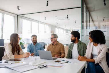 Modern bir ofiste dinamik bir iş görüşmesi yapan farklı bir ekip. İşbirliği ve takım çalışması yaratıcılığı ve verimliliği yönlendirir. İş, liderlik ve takım çalışması kavramları için ideal.