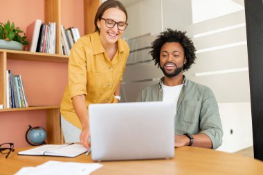 Kadın ve erkek ofiste dikilirken dizüstü bilgisayara bakıyorlar, iş arkadaşları proje hakkında tartışıyorlar, iki iş arkadaşı birlikte beyin fırtınası yapıyorlar.