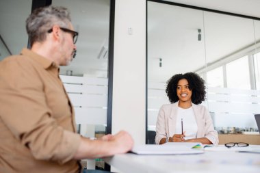 Dizüstü bilgisayarlar ve iş belgeleriyle konferans odasında işbirliği yapan çeşitli profesyonellerden oluşan bir ekip. Yenilik ve takım çalışması kurumsal başarıyı tetikler