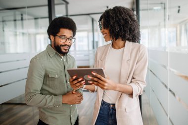 Modern bir ofiste dijital tablet üzerinde çalışan iki iş adamı. Takım çalışması, üretkenlik ve kurumsal başarıya odaklanmış işbirlikçi bir ortam.