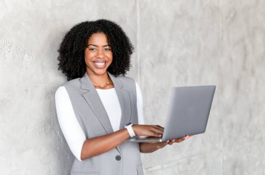 Diz üstü bilgisayarı ve daktiloyla yazı yazan neşeli Afro-Amerikalı iş kadını, ileri görüşlü yaklaşımını vurgulayan dokulu bir geçmişe sahip teknoloji güdümlü bir iş inovasyonunun sembolüdür.