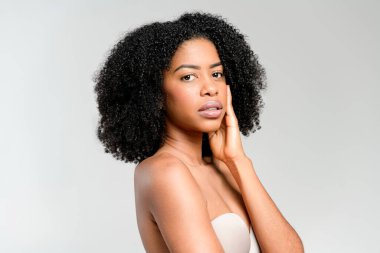 İçsel bir Afro-Amerikalı kadın düşünceli bir duruş sergiliyor, bakışları hafifçe başka yöne çevrilmiş, yansıtıcı ruh halini vurgulayan temiz bir arka plana karşı..