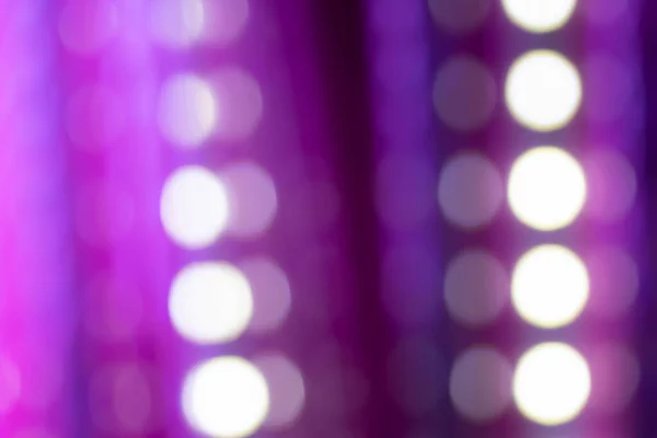 Neon purple bokeh background with various defocused lines and light circles on dark. Blurry night lights retro glow for using as background or overlay. Natural light and lens effect.