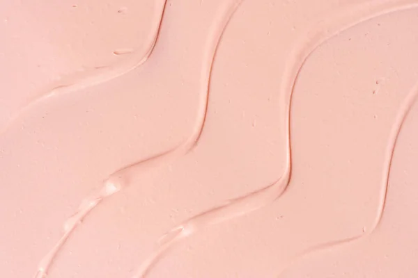 Pink cosmetic clay wavy smudged background. Pink cleanser cosmetic texture background. Pink clay cosmetic mask textured smears macro backdrop. Cosmetic clay for face and body skin care procedures.