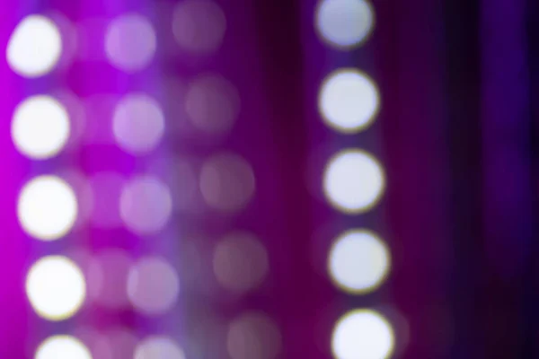 Neon purple bokeh background with various defocused lines and light circles on dark. Blurry night lights retro glow for using as background or overlay. Natural light and lens effect.