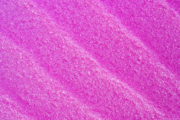 Texture of raspberry salt scrub, closeup. Smudges and strokes with salt particles. Skincare product for exfoliating and peeling. Colorful modern cosmetic product. Scrub texture as cosmetic background.