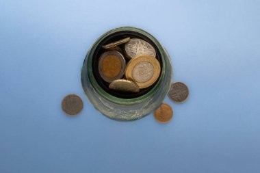 saving Colombian coins in a glass cup clipart