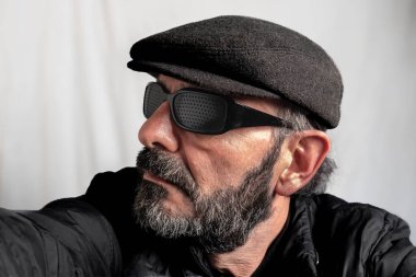 Şapkalı ve güneş gözlüklü olgun sakallı adam.