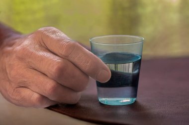 Bir adamın eli bir bardak Kolombiyalı Aguardiente tutuyor, tipik bir Kolombiya içkisi..