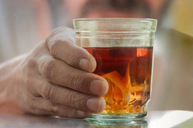 Gölgelerde elinde bir bardak alkol tutan bir adam