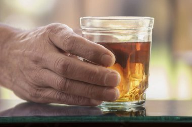 Gölgelerde elinde bir bardak alkol tutan bir adam