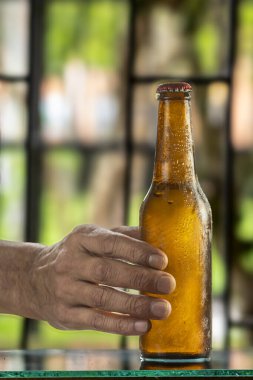 Elinde bira şişesi olan bir adam..