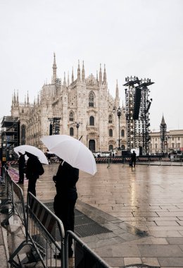 Milano 'daki Piazza del Duomo' nun panoramik manzarası yağmurlu bir günde beyaz şemsiyeli insanlarla