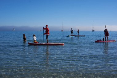 Noel Baba gibi giyinmiş bir grup insan Cagliari 'deki Poetto plajında kürek çekiyorlar - Sardunya - İtalya 2022