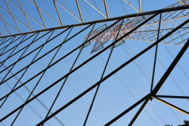 Elektrik direğinin gökyüzüne karşı düşük açılı görüntüsü, elektrik ağının yüksekliğini ve yapısını vurguluyor.