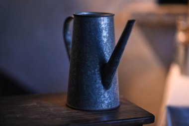 Bir metal sürahi bir masaya yerleştirilir, parlak tasarımı ve kırsal cazibesi vurgulanır, içecek servisi için ideal ya da dekoratif bir parça olarak.