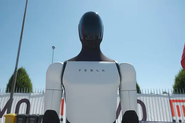 Açık mavi gökyüzüne karşı sergilenen, parlak tasarımı ve gelişmiş teknolojisiyle gelecekçi bir Tesla insansı robotu..