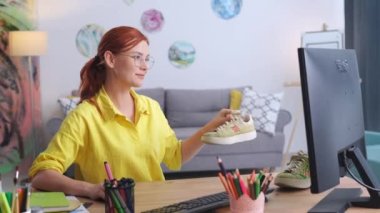 yaratıcı kadın tasarımcı evde otururken tasarımı ortaya çıkarmak için keçeli kalemle spor ayakkabı çiziyor.