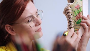 Kumaş uçlu kalemler kullanan yaratıcı kadın portresi spor ayakkabılarında yeni moda izler yaratıyor, eski ayakkabıları yeniden tasarlıyor.