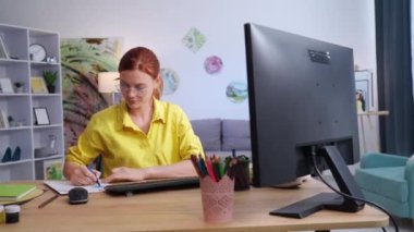 Tasarımcı, gözlüklü genç yaratıcı kadın masada oturan keçeli kalemleri kullanarak kağıda yazı çiziyor.