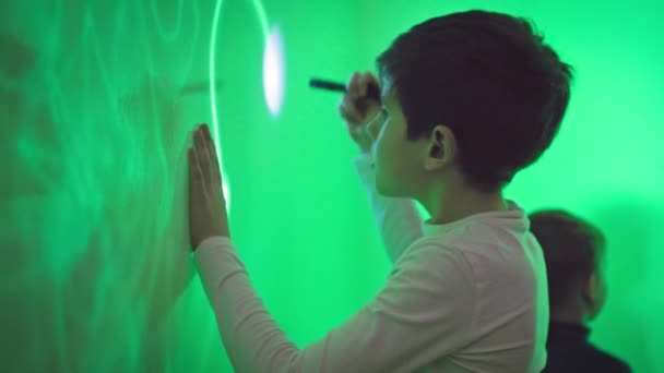 Современное Образование Детей Заинтересованный Мальчик Рисует Рисунок Ультрафиолетовым Фонариком Зеленой — стоковое видео