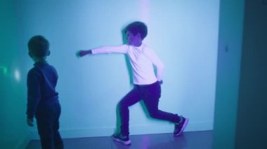 Çocukların gelişimi ve öğrenimi, mutlu çocuk kardeşiyle etkileşimli odada oynuyor ve bilim ve fiziği kullanarak duvarda bir gölge izi bırakıyor.