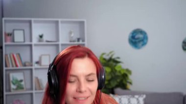 happy housewife in headphones having fun dancing and singing with a mop in hands while cleaning apartment