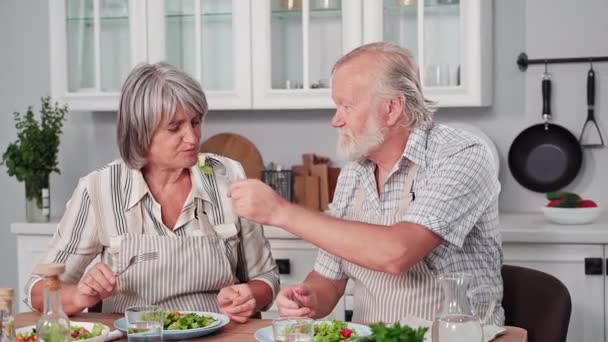 Familjemiddag Glad Äldre Par Bantning Och Äta Färsk Grönsakssallad Sittande — Stockvideo