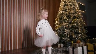 winter holidays, female girl continued dancing near the Christmas tree during New Years Eve party at home