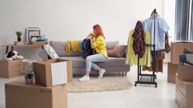 evacuation, young woman collects things in a backpack and a box and leaves house due to danger and war in the country