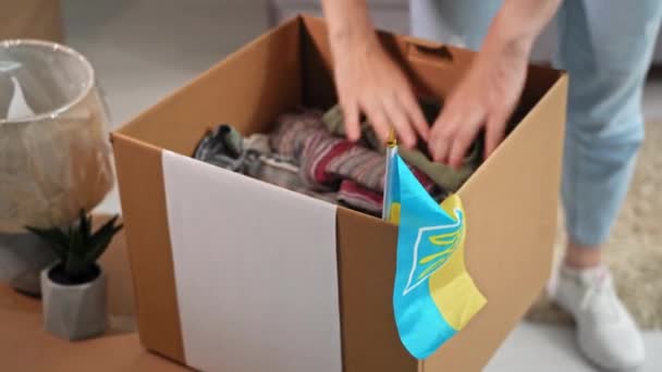 Žena Ruka Dává Oblečení Kartonové Krabici Vlajkou Ukrajinské Opustit Dům — Stock video