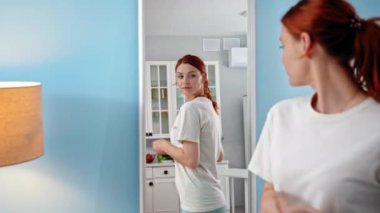 proper nutrition, charming young woman dieting goes to mirror and measures waist with sewing meter, smiles and looks in mirror, enjoying result