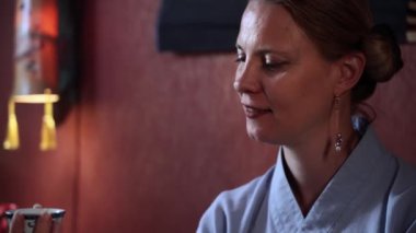 portrait of a joyful adult female tea master holding a tea ceremony indoors, smiling and looking at camera