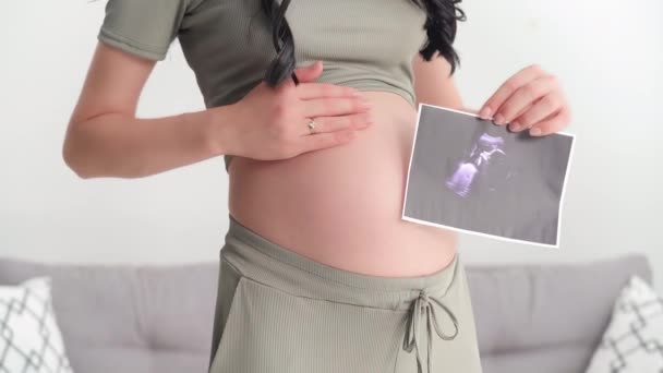 漂亮孕妇的肖像 手上拿着超声波照片 微笑着看着相机 — 图库视频影像