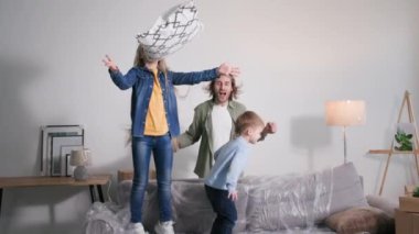 Aile taşınmayı kutluyor, mutlu bir ebeveyn, mutlu bir kız ve oğlu var. Yeni bir dairede mobilyaların arasında kanepede zıplayarak eğleniyorlar.